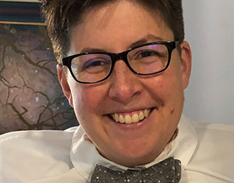 close-up photo of L.C. in a white shirt and gray bowtie, smiling