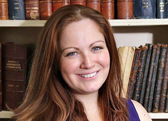 photo of Amy seated in front of a bookshelf full of antique books at West Point.