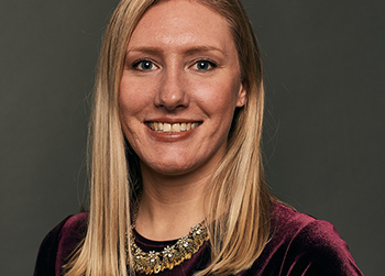 photo of Catherine. She has blond hair and is wearing a gold necklace and purple dress