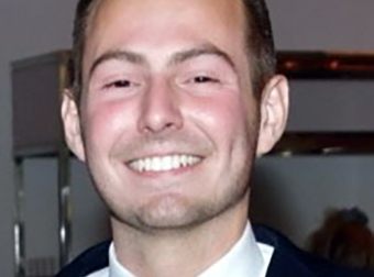 photo of Elijah, smiling, wearing an orange striped tie and a blue jacket