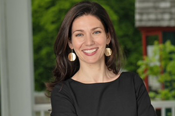Photo of Jessica in a black dress standing on the porch of a historic building
