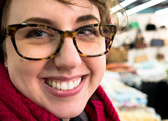 close up photo of Margot smiling into the camera. She wears tortoise shell glasses and a fuschia scarf.