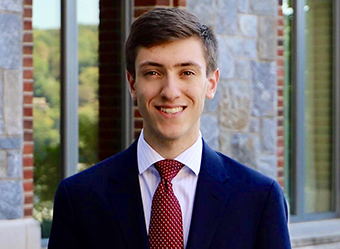 close up of Spencer wearing a red tie and dark blue suit.