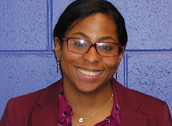 photo of Tracy, smiling. She is wearing a red blazer and purple shirt..