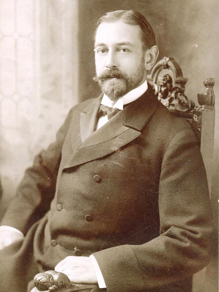 formal black and white photo of a seated man with a beard and mustache
