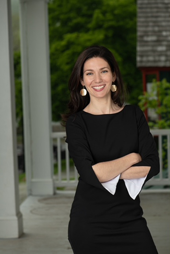photo of Jessica, smiling, wearing a black dress on the porch of a historic building
