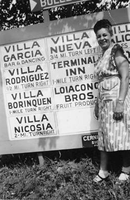 woman standing in front of a sign that advertises villas and their addresses